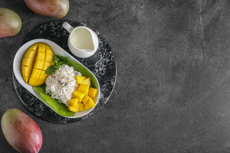 Plate with tasty rice and mango on dark backgroundの写真素材