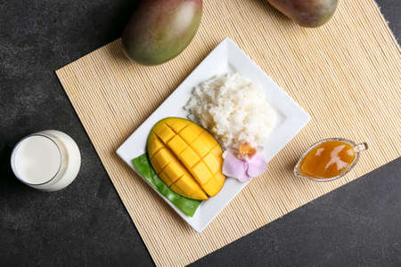 Plate with tasty rice and mango on dark backgroundの写真素材