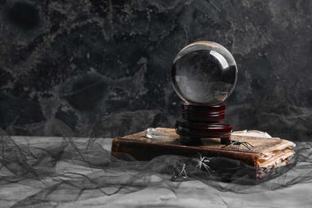 Crystal ball of fortune teller and old book on dark background