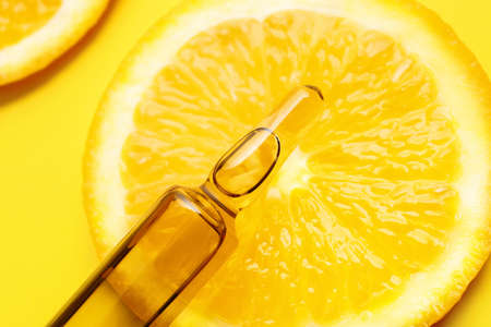 Ampule with vitamin C injection and orange fruit slice on color backgroundの写真素材