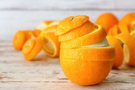 Fresh orange with peel on white wooden background
