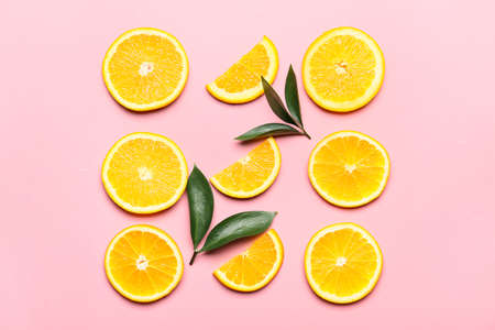 Slices of fresh oranges with green leaves on color background