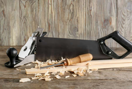 Set of carpenter's tools and saw dust on wooden background