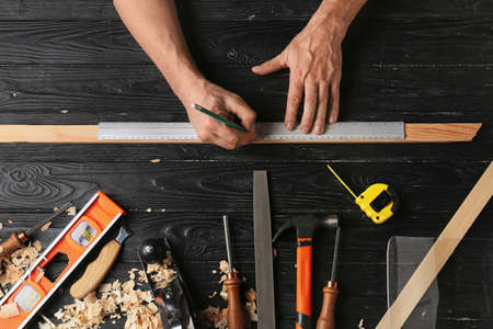 Carpenter marking wooden plank on dark backgroundの写真素材