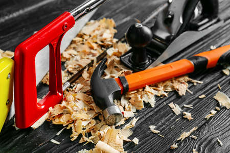 Set of carpenter's tools and saw dust on dark wooden background, closeup