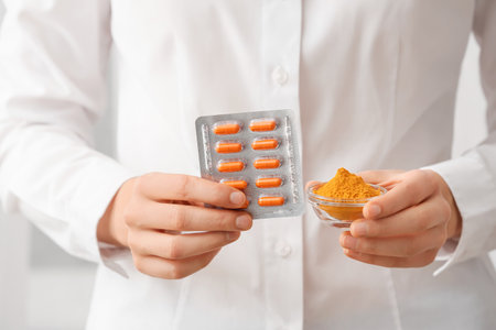 Female doctor holding blister pack of turmeric pills and powder, closeupの写真素材