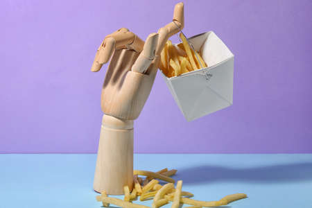 Wooden hand with tasty french fries on color backgroundの写真素材