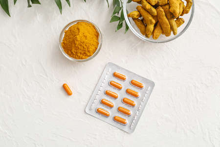 Blister pack with turmeric pills, roots and powder on light backgroundの写真素材