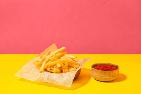 Tasty french fries and sauce on color backgroundの写真素材