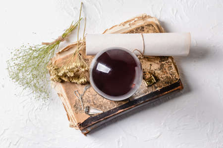 Crystal ball of fortune teller, spell book and scroll on tableの写真素材