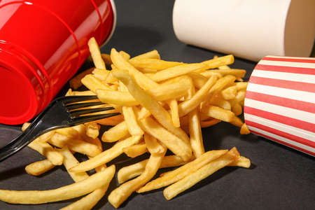 Cups and tasty french fries on dark backgroundの写真素材