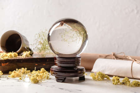 Crystal ball of fortune teller, spell book and scrolls on tableの写真素材