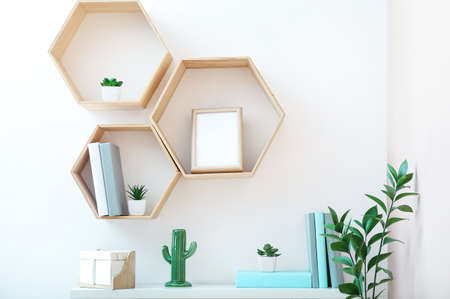 Shelves with books, frame and decor hanging on light wallの写真素材