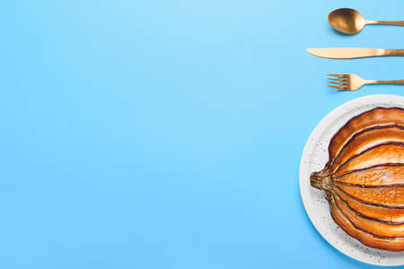 Beautiful plate in shape of pumpkin and cutlery on color backgroundの写真素材