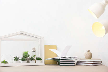 Books and florarium on table near light wallの写真素材