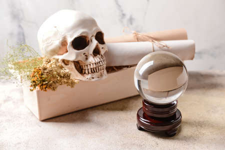 Crystal ball of fortune teller, human skull and box with ingredients for vial on tableの写真素材
