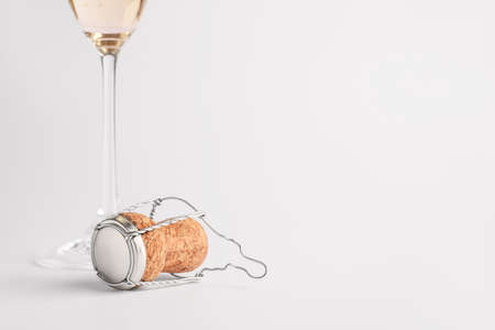 Glass of champagne and cork on light backgroundの写真素材
