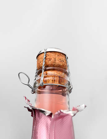 Bottle of champagne with cork on light background, closeup