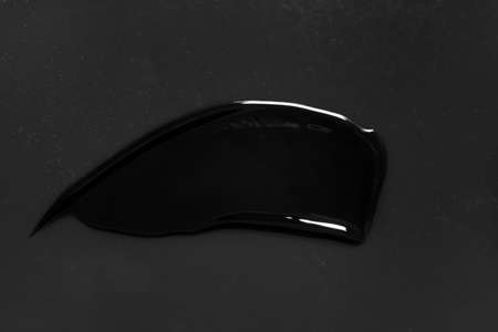 Stroke of black paint on dark background, closeup