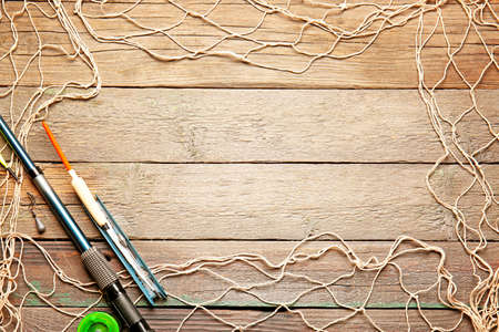 Frame made of fishing gear on wooden background
