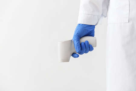 Doctor with infrared thermometer on white background, closeupの写真素材