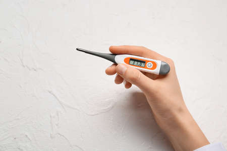 Female hand with electronic thermometer on white background