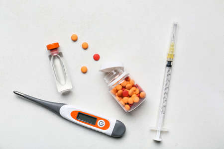 Electronic thermometer with pills, vaccine and syringe on white backgroundの写真素材