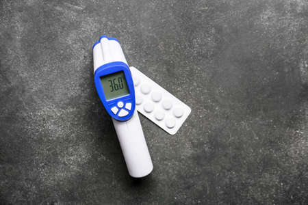 Infrared thermometer with pills on dark background