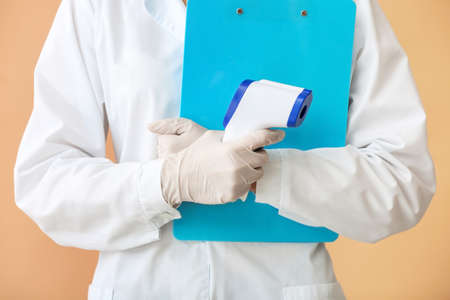Doctor with infrared thermometer on color background, closeupの写真素材