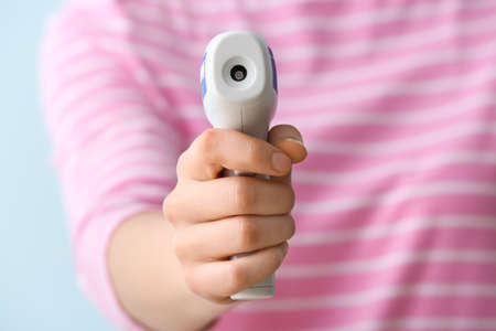 Woman with infrared thermometer on color background, closeupの写真素材