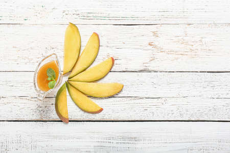 Gravy-boat with tasty mango sauce on white wooden backgroundの写真素材