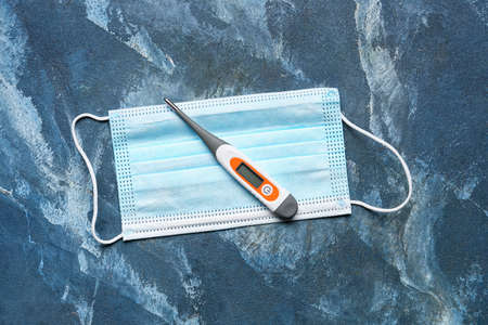 Electronic thermometer with medical mask on color backgroundの写真素材