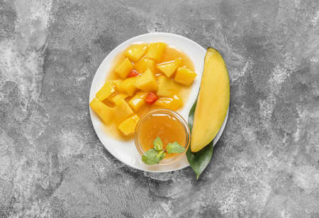 Plate with tasty mango salad and sauce on gray backgroundの写真素材