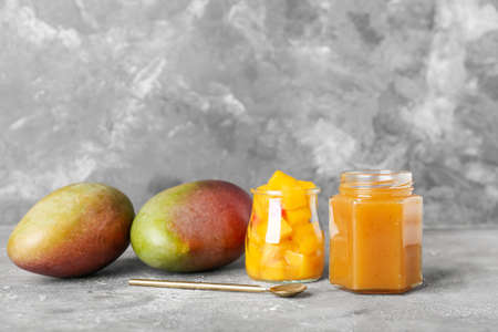 Jar with tasty mango sauce and salad on gray backgroundの写真素材