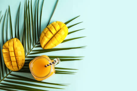 Mason jar of fresh mango juice on color background