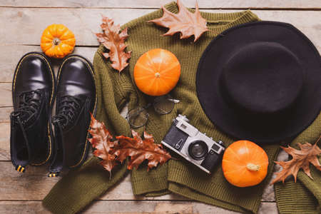Beautiful autumn composition with clothes and photo camera on wooden background