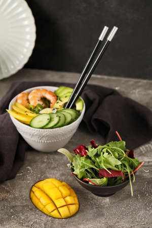Bowl of fresh salad with mango, shrimps and vegetables on gray backgroundの写真素材
