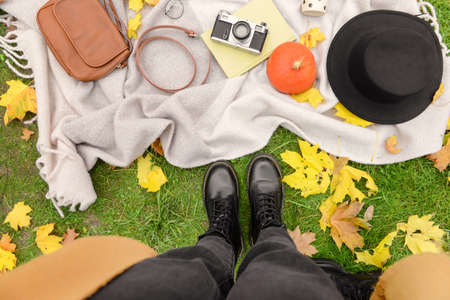 Female accessories with book and photo camera on plaid in autumn parkの写真素材