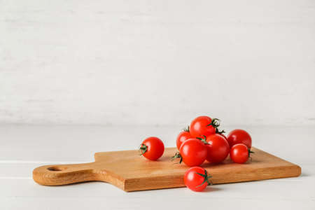 Cutting board with tomatoes on light wooden backgroundの写真素材