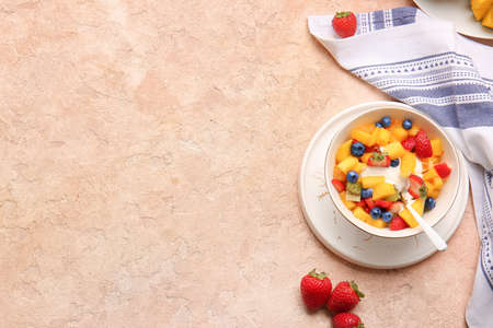 Bowl with tropical fruit salad on color background