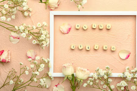Cubes with text HELLO SPRING and beautiful flowers on color background