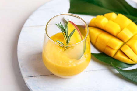 Glass of tasty mango margarita on light wooden backgroundの写真素材