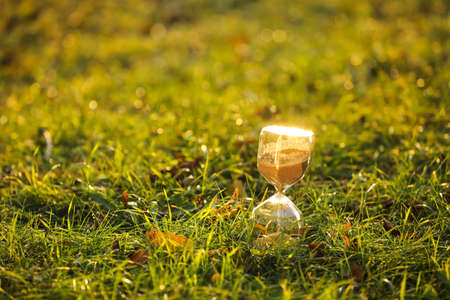 Stylish hourglass on grass outdoors