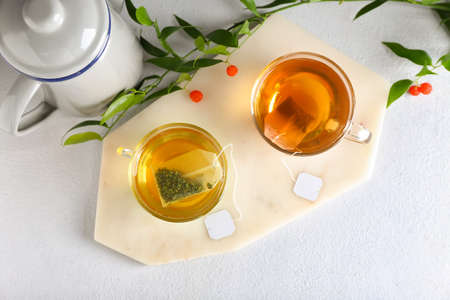 Cups of aromatic green and black tea on light backgroundの写真素材