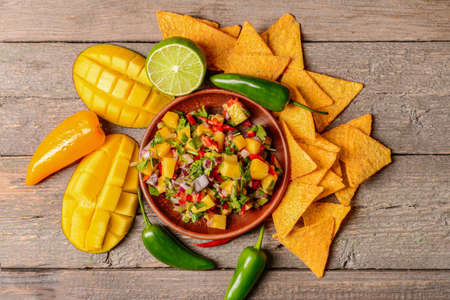 Plate with fresh mango salsa and nachos on wooden backgroundの写真素材