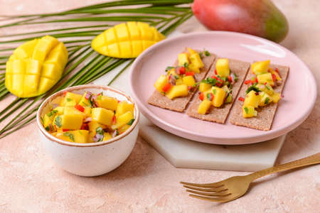 Plate with crispbreads and fresh mango salsa on color backgroundの写真素材