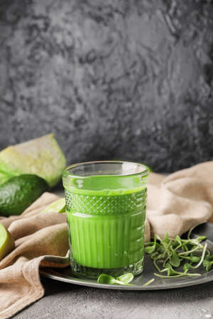 Glass of healthy green smoothie and ingredients on dark backgroundの写真素材