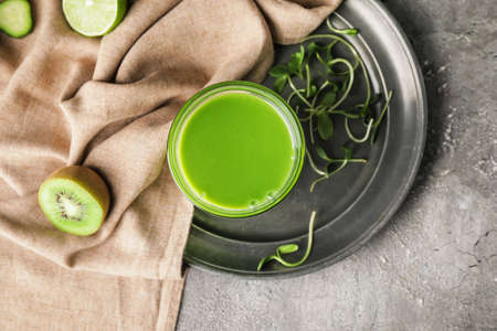 Glass of healthy green smoothie and ingredients on dark backgroundの写真素材