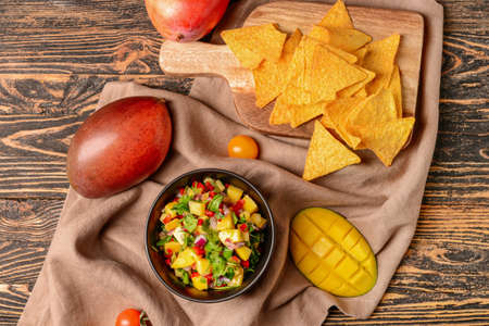 Bowl with fresh mango salsa and nachos on wooden backgroundの写真素材