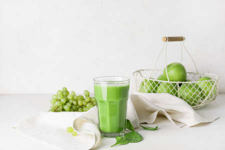 Glass of healthy green smoothie and ingredients on light backgroundの写真素材